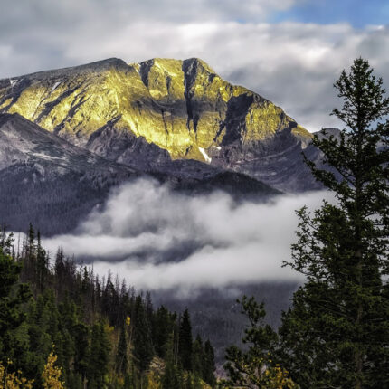 colorado mountains with low clouds and sun peeking through