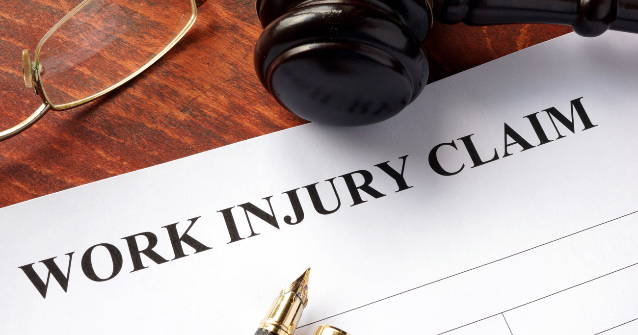 work injury claim paperwork with gavel, fountain pen, and mens glasses near paperwork Ridder Law Denver Colorado